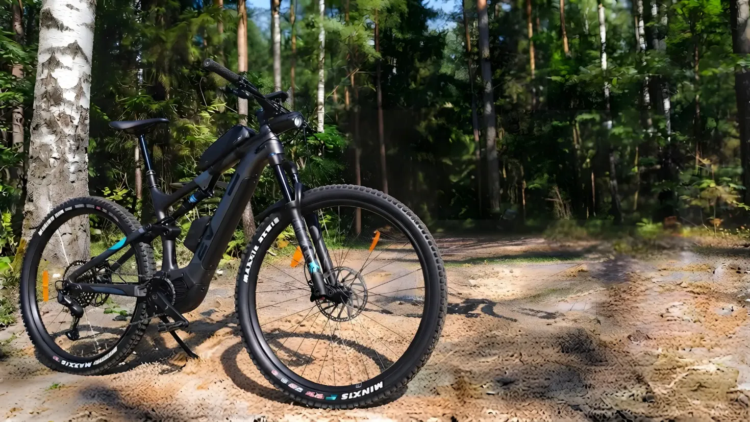 Black full-suspension electric mountain bike parked on a forest trail, next to a birch tree trunk.